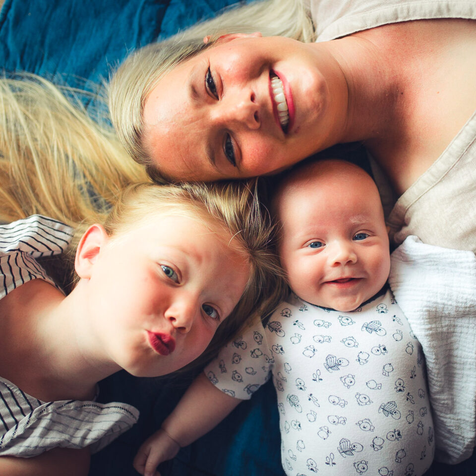 Familienglück: Mutter mit zwei Kindern lachend auf dem Boden