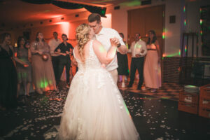 Braut und Bräutigam küssen sich beim Hochzeitstanz, umgeben von applaudierenden Gästen