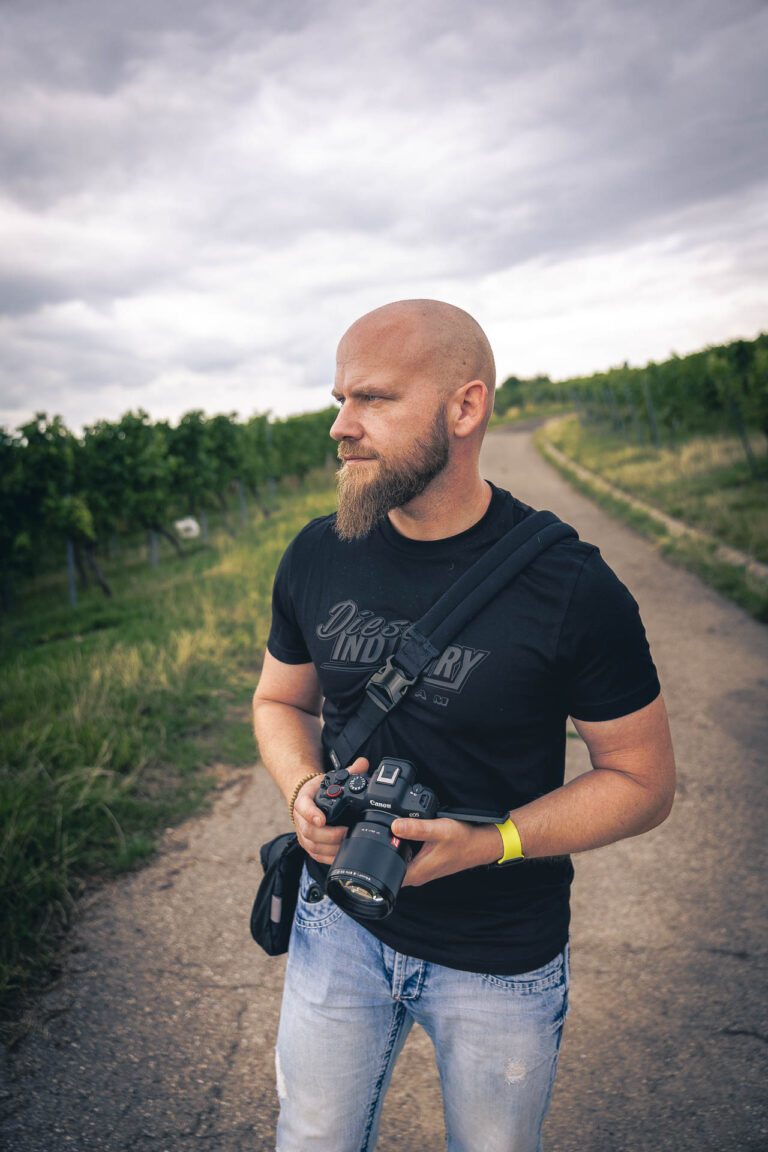 Mann mit Bart und Kamera im Weinberg – authentisches Outdoor-Fotografenportrait mit Canon R